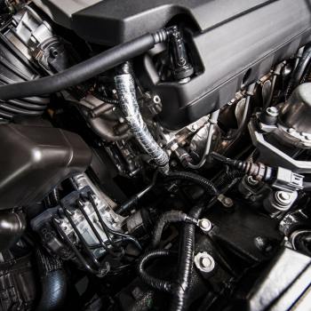 Close-up image of a vehicle's fluid control system within the engine bay, showing solenoid valves and their connection to hoses and pipes, essential for precise management of fluids in automotive applications